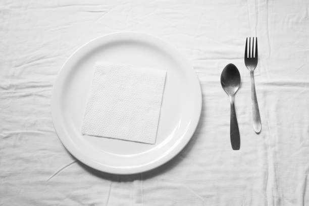 Set of clean spoon fork and white ceramic plate and white tissue paper on the white background