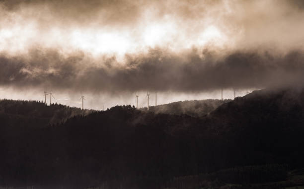 Wind turbines on mountains with dramatic sky during winter in northwest of Spain. Sustainability and renewable energy. Tranquility and exploration.