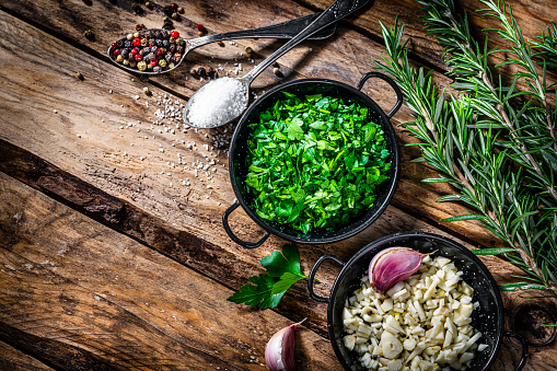 Chopped garlic and parsley, salt and pepper on wooden table