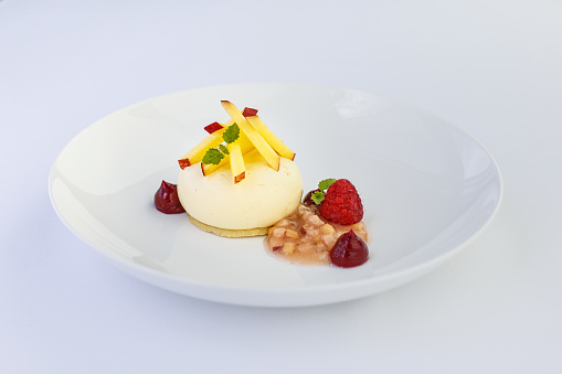 A Peach Melba elegantly plated in a fine dining setting or restaurant