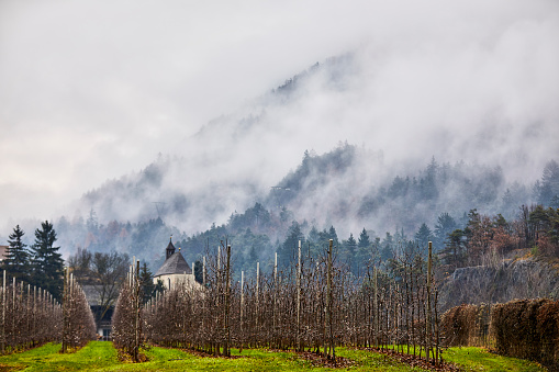 Church in a field with the mountains in the back in the mist, Dolomites, Italy