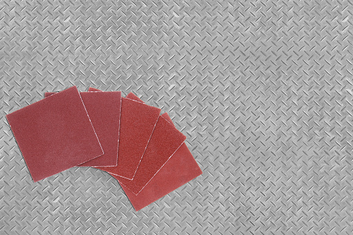 A group of sanding papers with different grits on a metal background