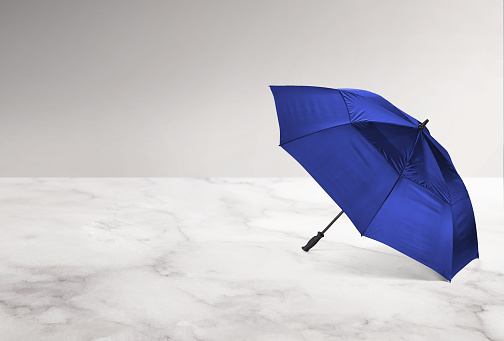 An open blue umbrella on a marble surface