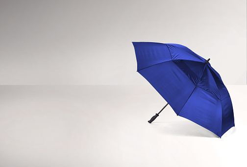 An open blue umbrella on a white surface