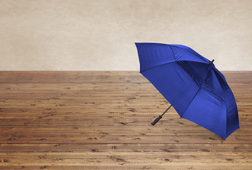 An open blue umbrella on a wood surface