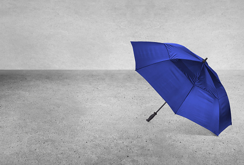 An open blue umbrella on a cement surface