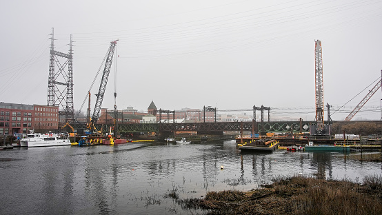 Norwalk, CT, USA - March 6, 2024: Industrial work place with Norwalk river in an urban area near railroad bridge