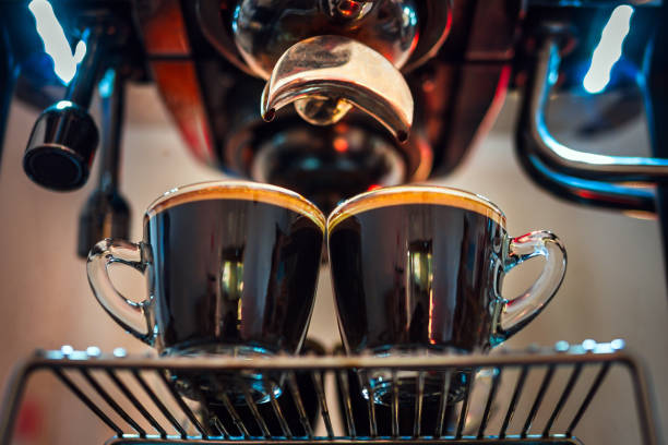 Close up of Espresso shot with coffee crema and Professional coffee machine while preparing two espressos shot glass in a coffee shop.