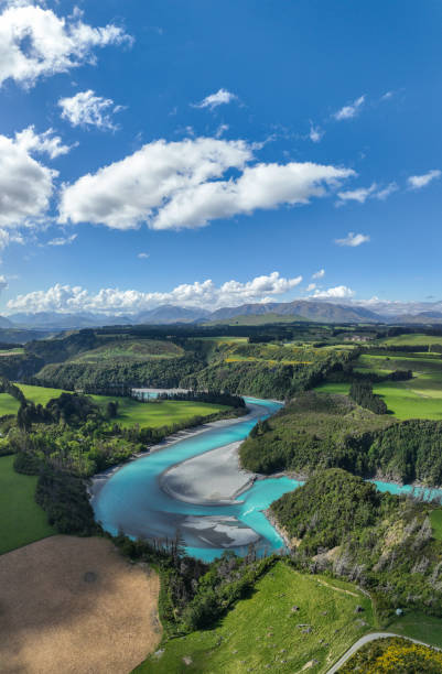 Experience the breathtaking allure of a winding glacier river amid lush green landscapes in New Zealand. Nature's masterpiece unfolds.