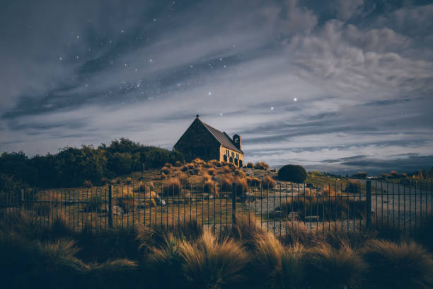 Experience the mesmerizing beauty of New Zealand's Church of the Good Shepherd under a starry night sky. A celestial spectacle awaits.