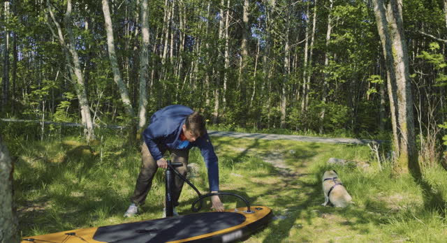 Man Preparing His SUP Board in the Forest