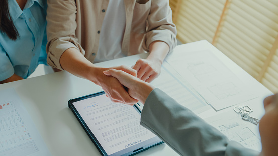 Close-up of Asian tenants sign house agreements on tablet and give them to female real estate agent after showing new houses. Landlord selling real estate to customers for investment concept.