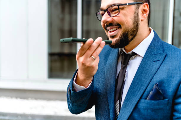 businessman sending a voice message outdoors - vocoder imagens e fotografias de stock