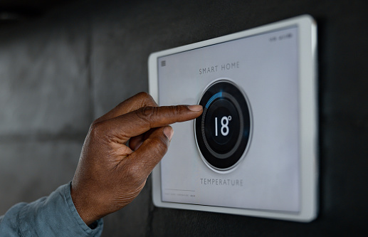 Close-up on a man adjusting the temperature of his house on a smart thermostat