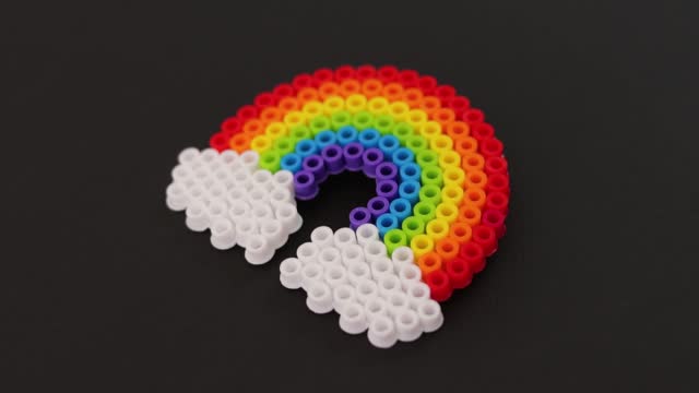 Colorful plastic bead rainbow on black background, vibrant craft project