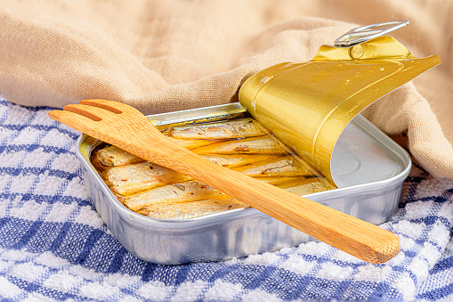 A can of Sardines in Oil with a wooden spatulas and a cloth