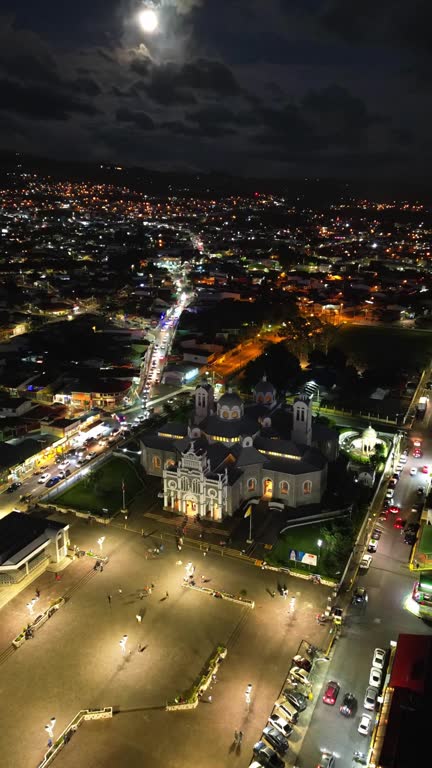 Drone vertical hyperlapse of Cartago cityscape with lights at night with full moon in Costa Rica