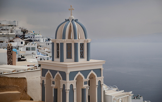 The distinguished blue dome of a Santorini church stands out against the dramatic backdrop of an impending storm.