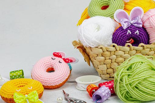 Set of clew of thread for knitting. Crocheted donuts bunnies, ribbons, handmade, Easter hobby concept. Props and special craft tools on light stone concrete background, copy space