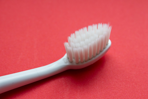 Used toothbrush isolated on red background. Old toothbrush. Top view, copy space.