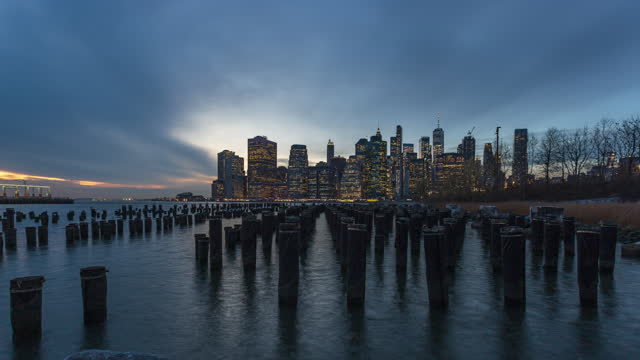 Wood Pilings At Old Pier 1 In Brooklyn Bridge Park With New York Financial District Skyline In USA. - timelapse