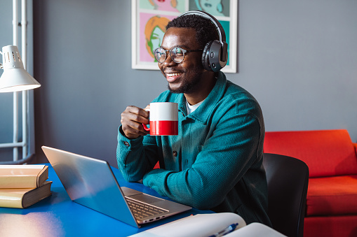 Young man enjoying in coffee while working on a laptop at home