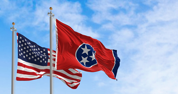 Tennessee state flag waving with the american flag on a clear day. Three white stars inside a blue circle on a red background with a white stripe and a blue band on the right. 3d illustration render