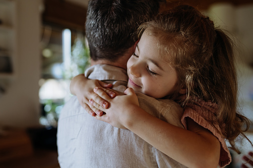 Daughter hugging father lovingly, closed eyes. Unconditional paternal love and care. Father's Day concept.