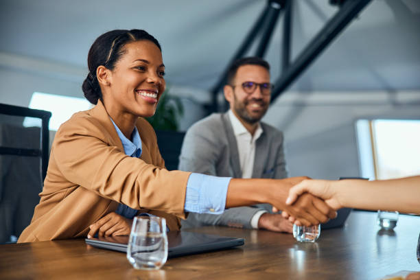 istock A smiling African female doing a handshake with a client while sitting next to her colleague. 2065959693