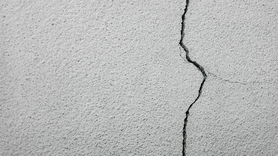 grey plaster facade hous wall with dark cracks