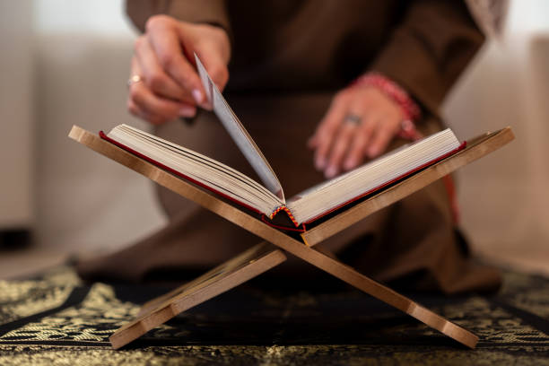 Muslim woman with Holy Quran praying at home
