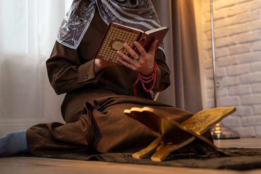 Muslim woman with Holy Quran praying at home