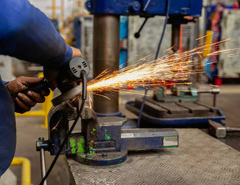 Heavy industry worker cutting steel with an angle grinder.