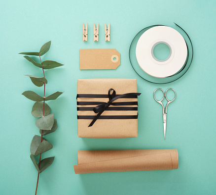 Summer gift wrapping. Brown craft wrapping paper, black ribbon, scissors, eucalyptus, tags.