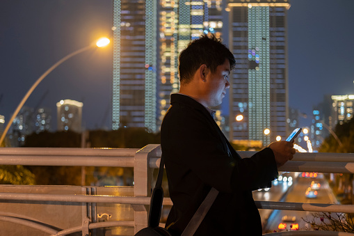 A man uses a smartphone under the lights at night in the city