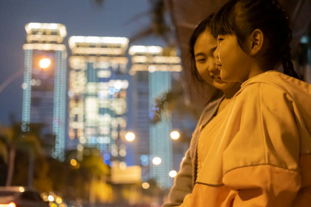 Asian mother and daughter waiting at bus stop