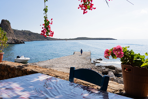 Close up of greek tavern table with Aegean sea as background decorated with brightly colored flowers and pots on a beautiful summer day