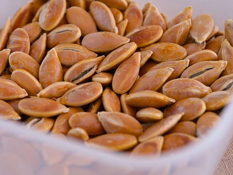 A close-up shot of a plastic container with pumpkin seeds.