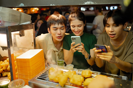 Attractive Tourist Chronicles Street Food Wonders with Smartphone at Night Market.