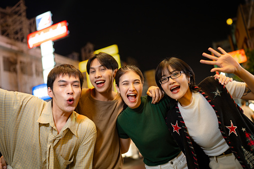 Asian friends take a selfie while walking through the vibrant streets of Yaowarat Road at Night.