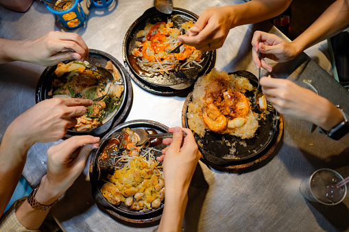 Asian tourist uses a smartphone to take a video of the food at the local restaurant Yaowarat Night Market.