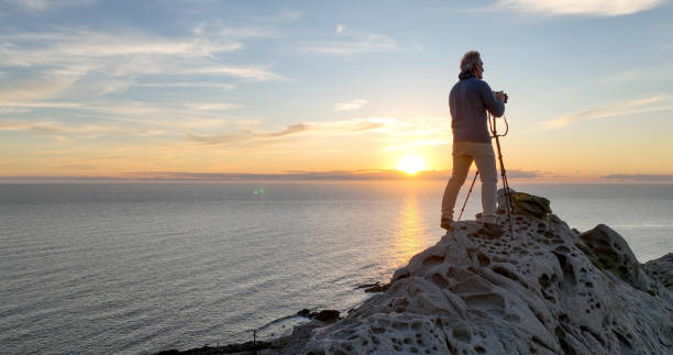 istock Mature man photographs on rock ridge crest 2066146633