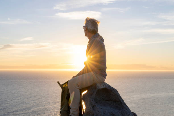 istock Mature man relaxes on rock ridge crest 2066146654