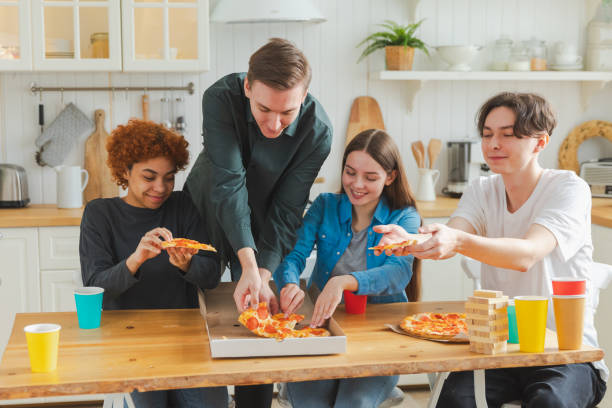 istock Home party. Overjoyed diverse friends eating ordered pizza for home party. Happy group multiracial young buddies enjoying spending free weekend time together having fun laughing joking communicating. 2066170321