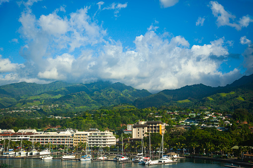 Tahiti island with green mountains and yachts at the pier.