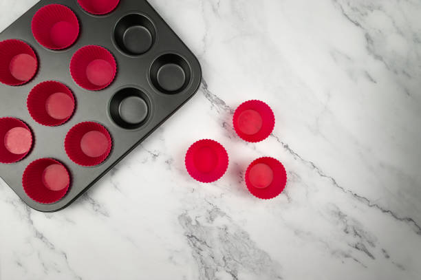 Top view of cupcake pan and silicone cases on white marble background.