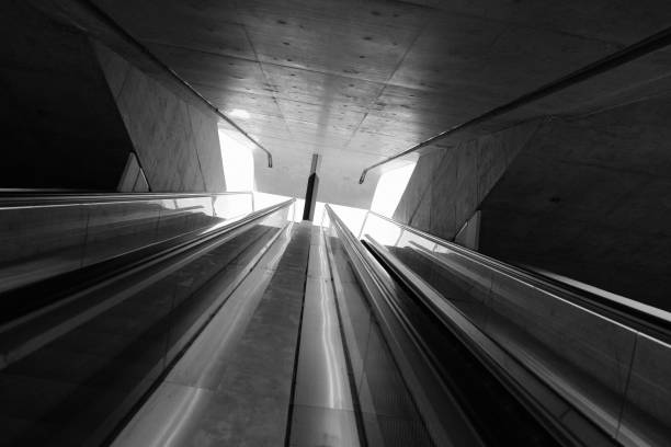 The Marconi metro station in Brescia, Italy, with escalators and stairs connecting different levels, characterised by a modern, futuristic design with a large dark wall.