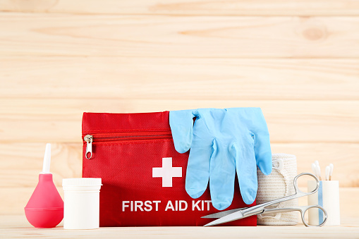 First aid kit with medical supplies on brown wooden table