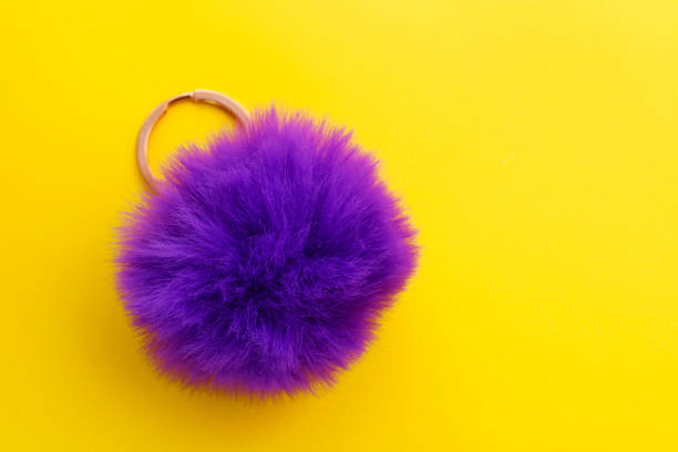 istock Keychain with purple pompom on yellow background 2066239219