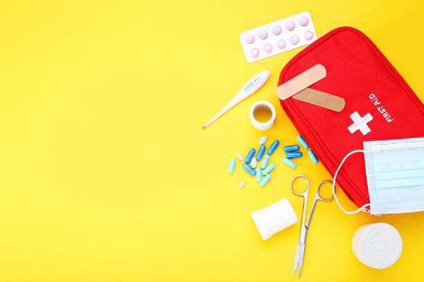 First aid kit with medical supplies on yellow background